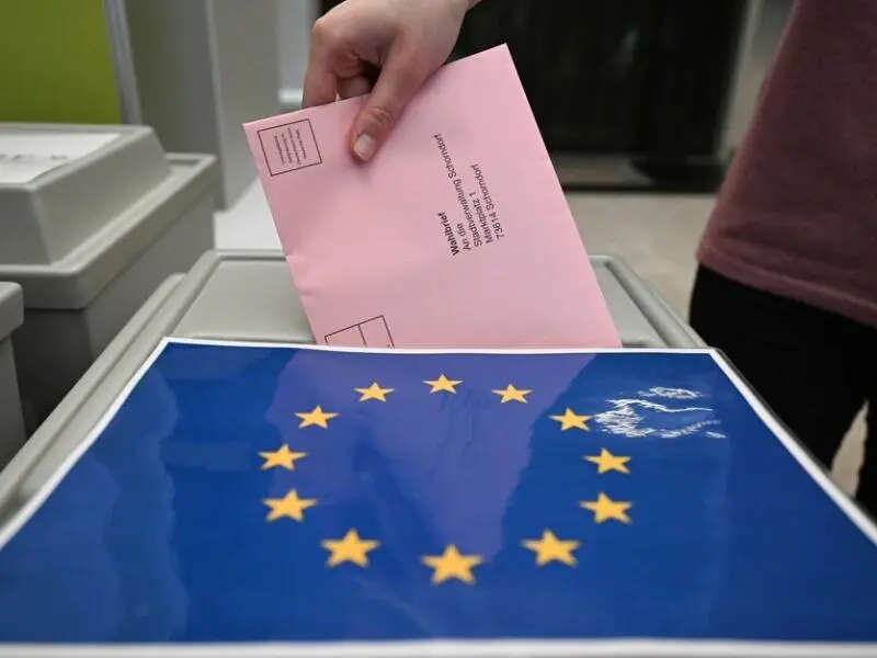 Eine Frau wirft einen Wahlbrief in eine Wahlurne