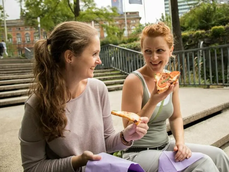 Zwei Frauen essen Pizza im Freien