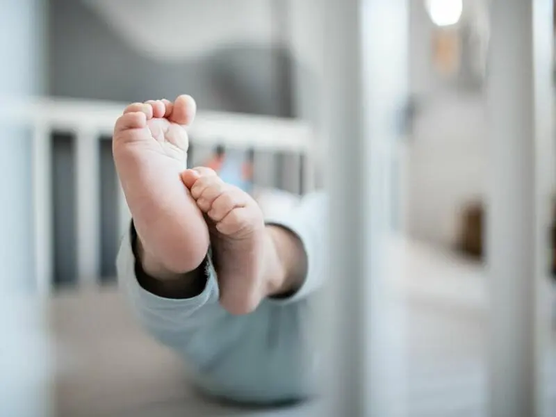 Ein Baby liegt in einem Beistellbett