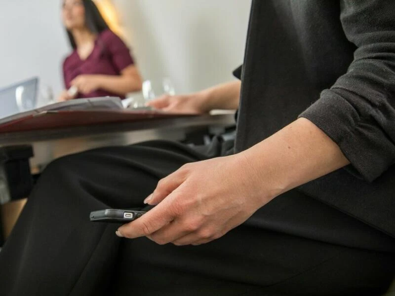 Eine Frau schaut heimlich auf ihr Smartphone