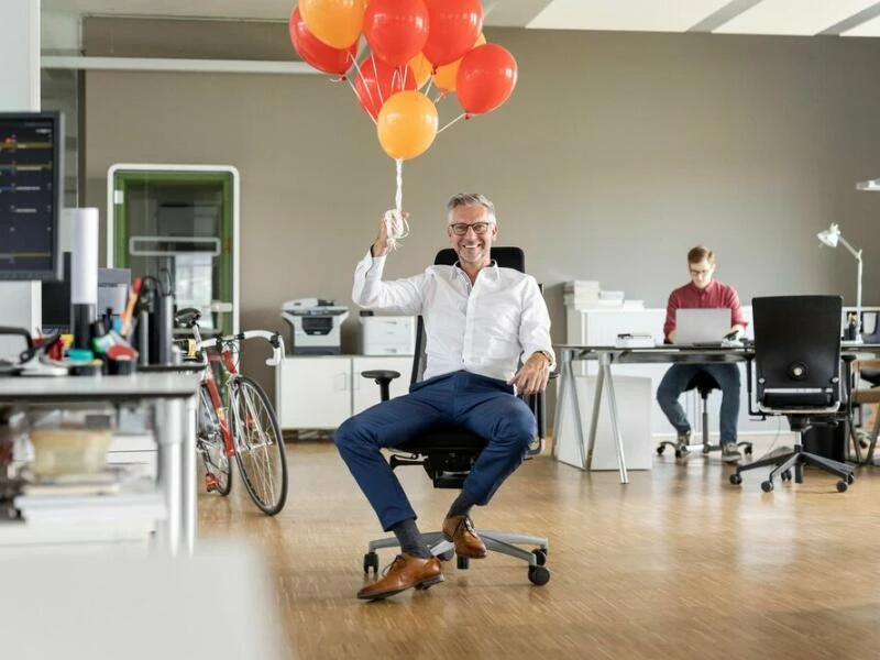 Mann mit Luftballons im Büro