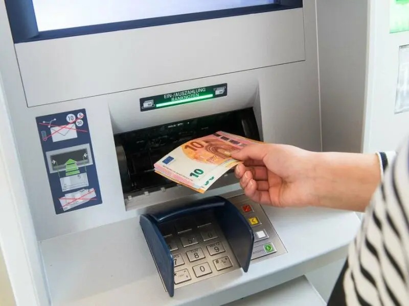 Eine Person holt Geld vom Automaten