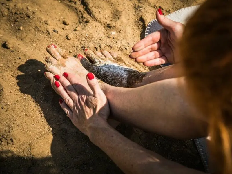 Frau entfernt Sand an ihren Füßen