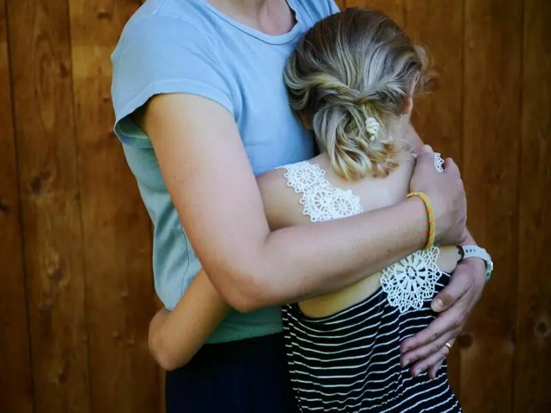 Ein Mädchen wird von seiner Mutter in den Arm genommen