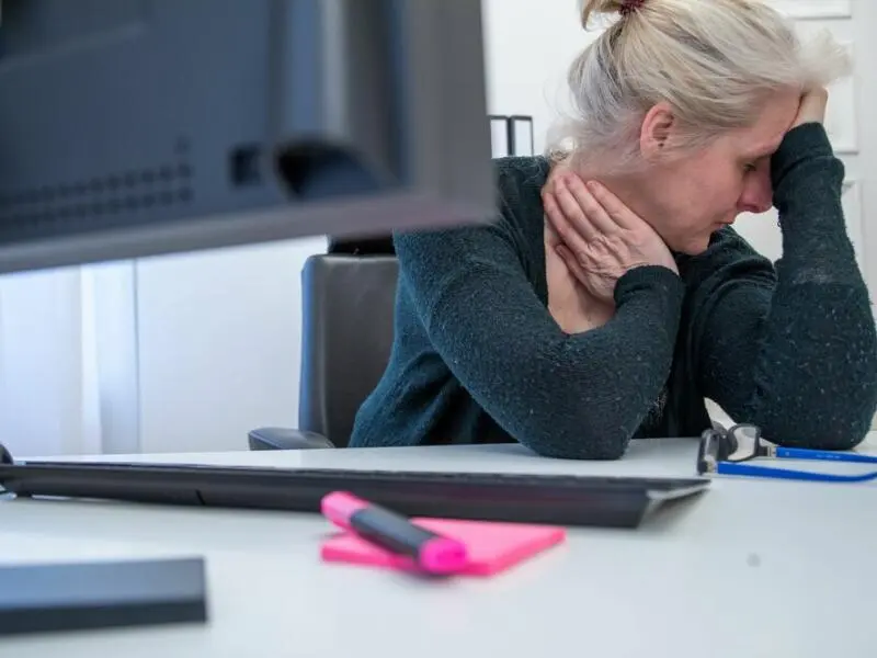 Eine Frau stützt ihren Kopf auf die Hand am Arbeitsplatz