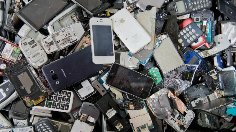 Alte Handys und Smartphones liegen in einem Container