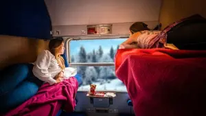 Zwei Personen im Zug blicken in eine Schneelandschaft