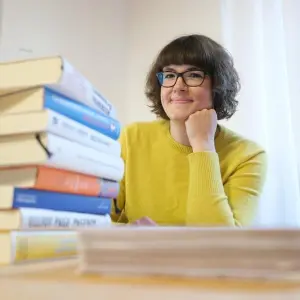 Lisa Kögeböhn vor einem Bücherstapel