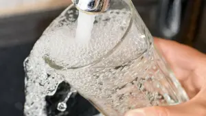 Eine Frau füllt ein Glas mit Trinkwasser aus dem Hahn