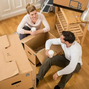 Ein Paar sitzt in einer Wohnung zwischen Umzugskisten