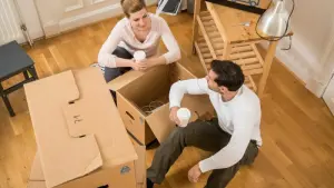 Ein Paar sitzt in einer Wohnung zwischen Umzugskisten