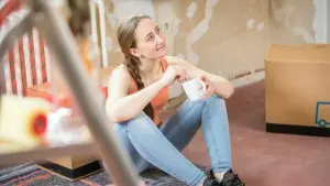 Junge Frau mit Kaffeebecher beim Renovieren