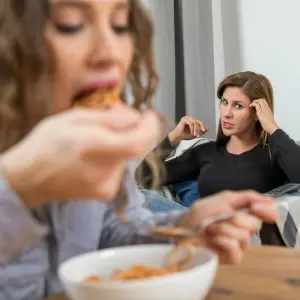 Zwei Frauen im Wohnzimmer, eine Frau isst.