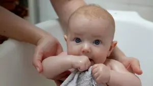 Person hält Baby in Badewanne