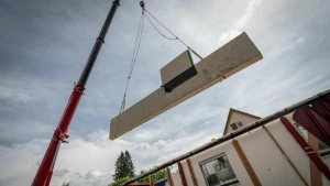 Ein Kran hebt eine vorgefertigte Wand auf einer Baustelle