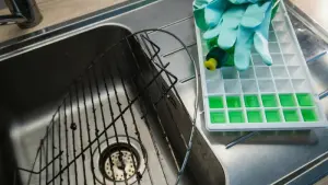 Schmutziger Grillrost neben Eiswürfeln aus Spülmittel