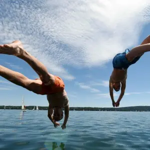 Zwei junge Männer springen am Starnberger See ins Wasser