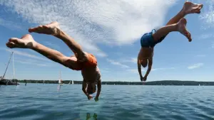 Zwei junge Männer springen am Starnberger See ins Wasser