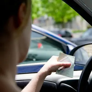 Eine Frau hält Fahrzeugpapiere in der Hand