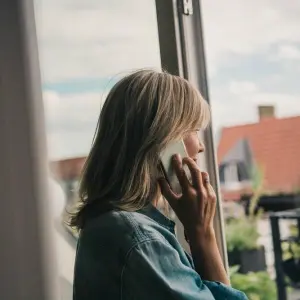 Eine Frau telefoniert am Fenster