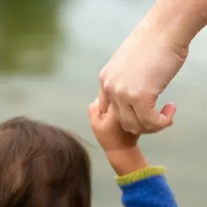 Ein Kind an der Hand einer erwachsenen Person