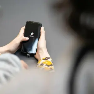 Jugendlicher schaut auf ein Smartphone mit der App von TikTok