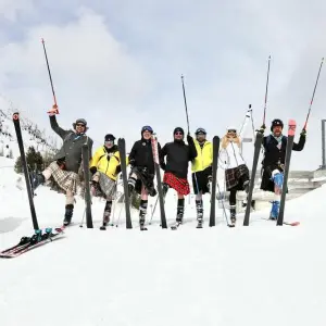 Eine Gruppe Kilt-Träger auf Skiern im Schnee.