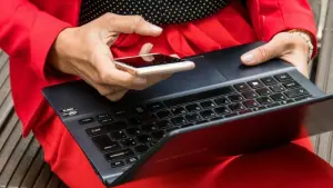 Eine Frau hält ein Smartphone und ein Laptop in den Händen
