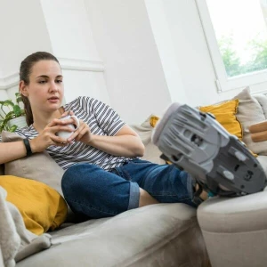 Eine Frau liegt mit einer Orthese auf dem Sofa