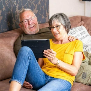 Ein Paar sitzt schaut auf ein Tablet