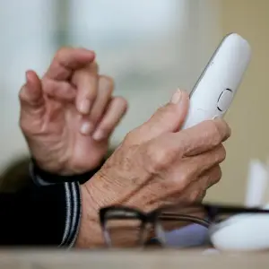 Rentner hält Telefon in der Hand
