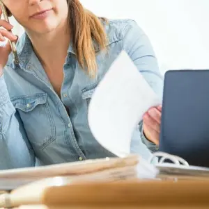 Eine Frau telefoniert und liest Unterlagen durch