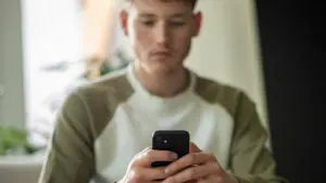 Ein junger Mann tippt auf seinem Handy