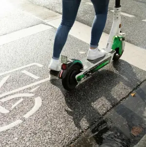 Eine Person fährt mit einem E-Roller auf einem Radweg