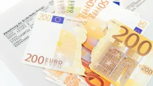 Ein zerissener 200-Euro-Schein liegt auf einer Gehaltsabrechnung