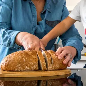 Zwei Menschen schneiden Brot