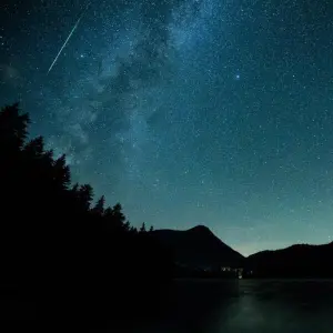 Eine Sternschnuppe leuchtet am Himmel über dem Walchense (Bayern)