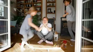 Gestresste Mutter sitzt zwischen dem Spielzeug ihrer Kinder