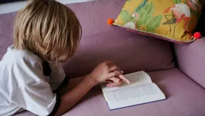 Ein Kind liegt auf dem Sofa und liest
