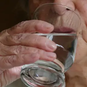 Eine Seniorin trinkt ein Glas Wasser