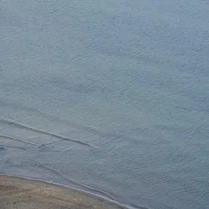 Eine Frau steht allein am Strand der Ostsee
