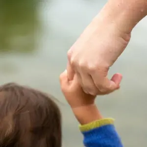 Ein Erwachsener hält die Hand eines Kindes.