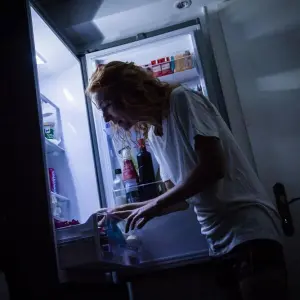 Eine Frau geht nachts an den Kühlschrank