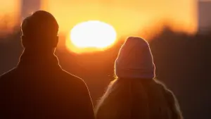 Ein Paar blickt nebeneinander in einen Sonnenuntergang