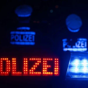 Zwei Polizisten stehen vor einem Streifenwagen