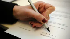 Eine Frau unterschreibt einen Arbeitsvertrag