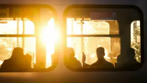Fahrgäste sitzen bei Sonnenaufgang in einer Stadtbahn