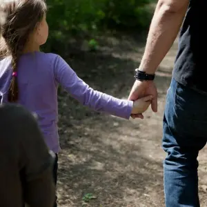 Ein Mann hält seine Tochter an der Hand