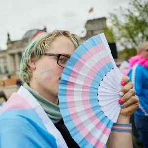 Amity hält einen Fächer in den Transgender-Farben