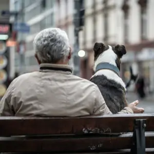 Ein älterer Herr und sein Hund sitzen auf einer Bank